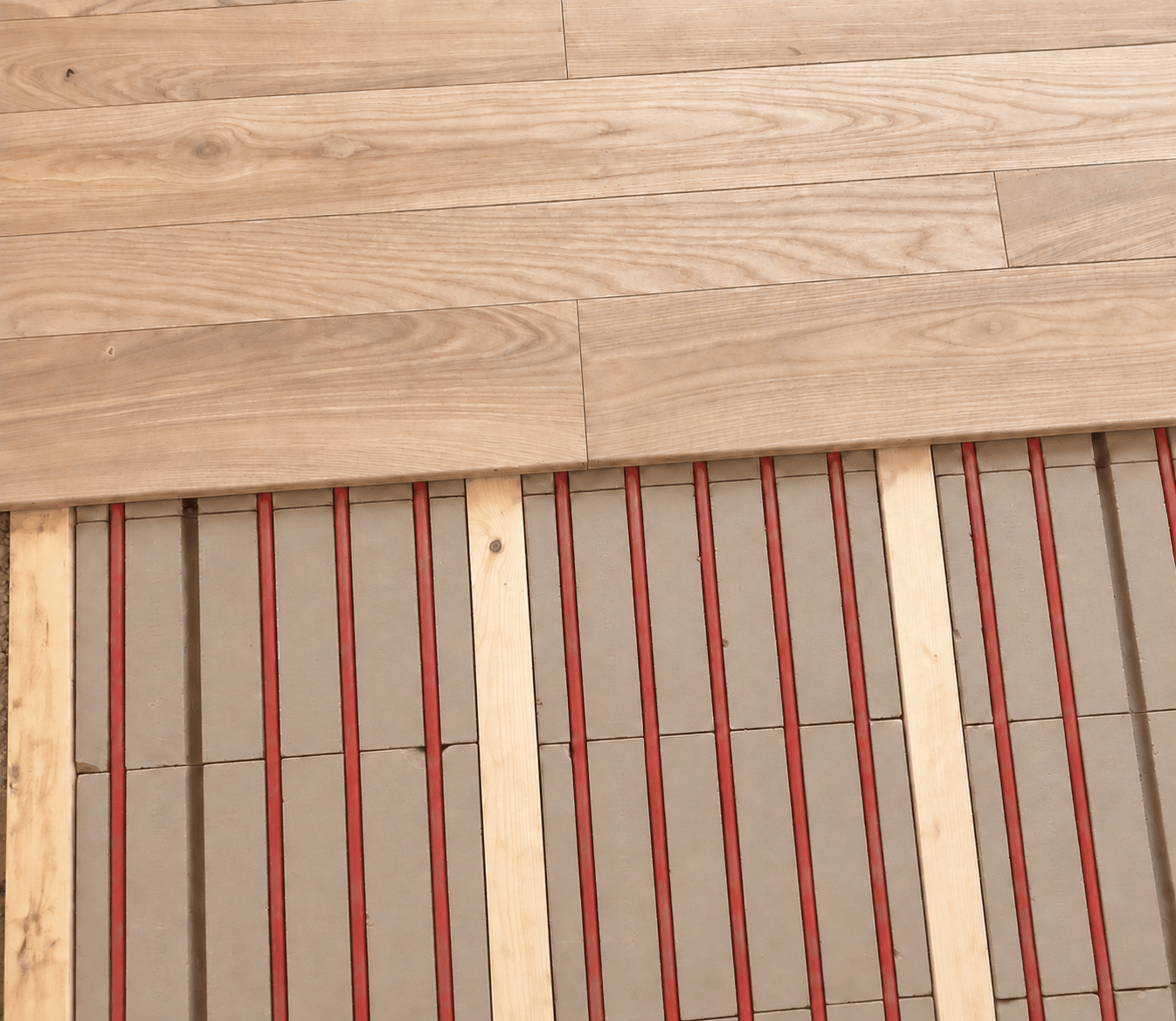 Massivholzdielen über den originalen Lethermo-Lehmelementen mit roten Heizrohren und Holzleisten.